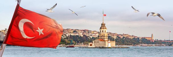 Panorama de Istambul com Maiden Tower, kiz kulesi, no horizonte e gaivotas sobre o mar, ampla paisagem com a bandeira turca em primeiro plano, fundo de viagem para outdoor
 - Foto, Imagem