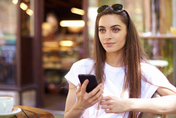 Retrato de jovem sentada no café e mensagens de texto
  - Foto, Imagem