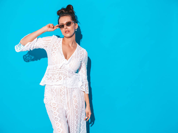 Portrait of young beautiful sexy woman with ghoul hairstyle. Trendy girl in casual summer white hipster suit clothes in sunglasses. Hot model isolated on blue  - Φωτογραφία, εικόνα
