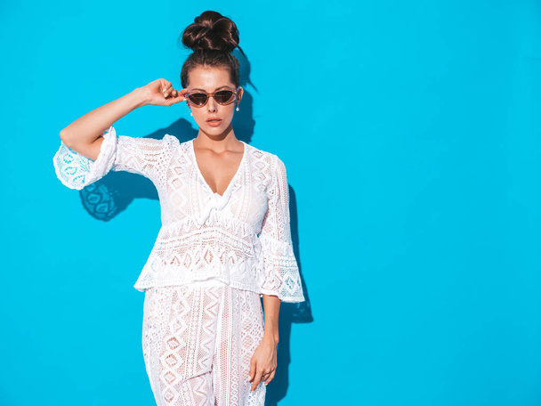 Portrait of young beautiful sexy woman with ghoul hairstyle. Trendy girl in casual summer white hipster suit clothes in sunglasses. Hot model isolated on blue  - Foto, Bild