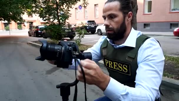 Professionele reporter Live in City Street. Een reporter met speciale kleren wandelingen door de straten van de stad, kiest locaties voor het filmen. - Video