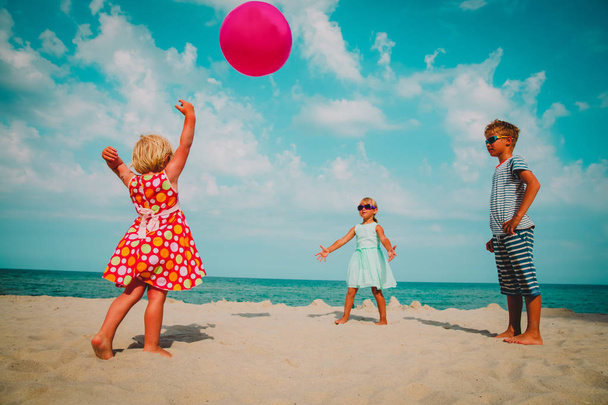 kids play with ball on beach vacation, boy and girls have fun at sea - 写真・画像