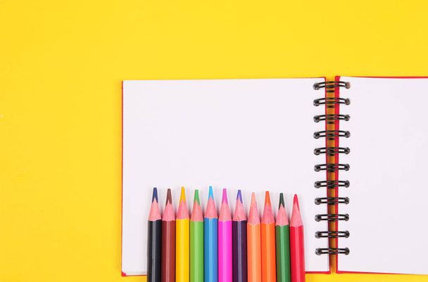 Buntstifte und Notizbuch mit Kopierraum auf gelbem Hintergrund, Bildung zurück in die Schule, Verkauf, Einkaufskonzept. - Foto, Bild