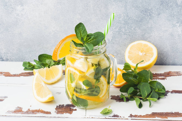 Lemonade drink of soda water, lemon and mint leaves in jar on light background. Copy space - Fotó, kép