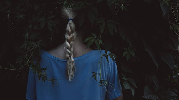 Girl with blonde hair on dark natural background - Fotoğraf, Görsel