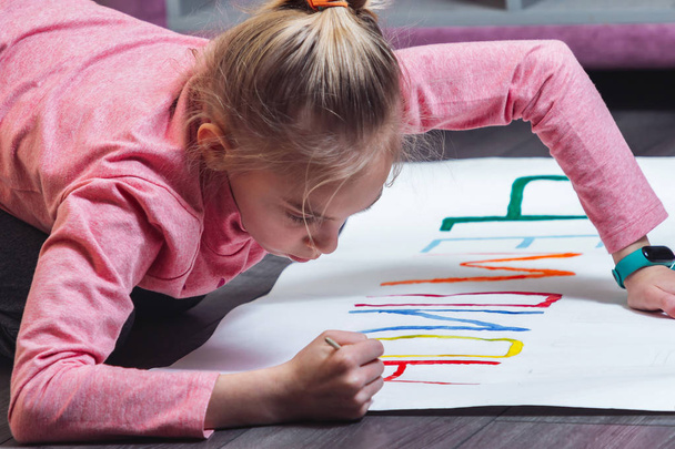Young girl draws on the floor with paints on paper - Foto, immagini