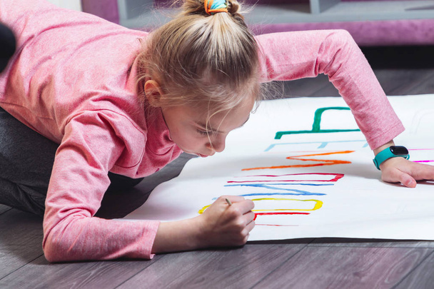 Young girl draws on the floor with paints on paper - Foto, immagini
