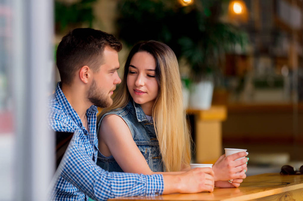 fiatal pár ül egy asztalnál egy kávézóban, és kávéfogyasztás - Fotó, kép