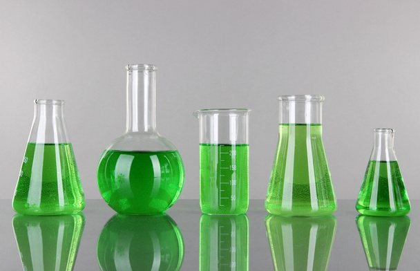 Test-tubes with green liquid on gray background - Foto, imagen