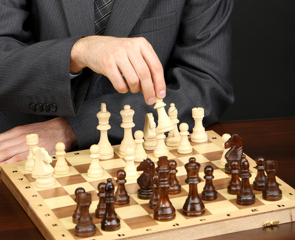 Young business man playing chess on black background - Fotó, kép