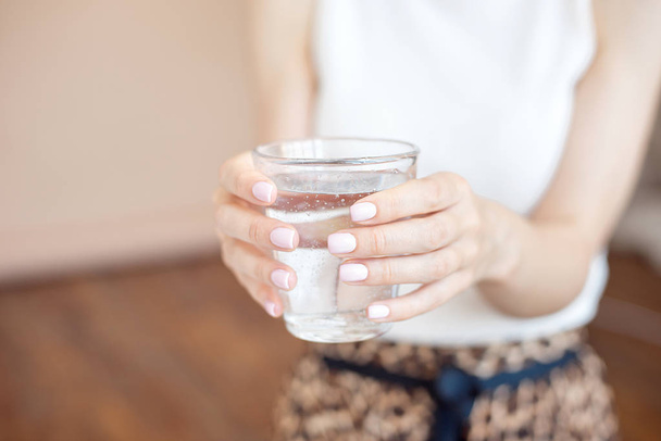 Manos femeninas sosteniendo un vaso de agua transparente. Un vaso de agua mineral limpia en las manos, bebida saludable
. - Foto, imagen