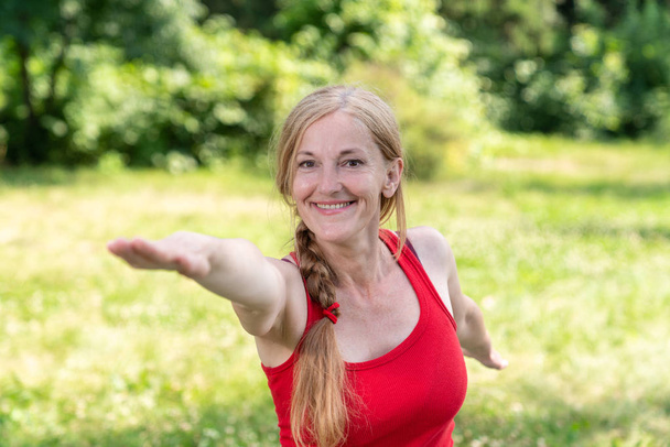Best aged lady practice yoga doing archer pose in a park - Fotoğraf, Görsel