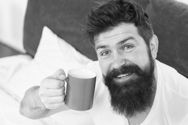 Caffeine addicted. Coffee fills you with energy. Good gay begins from cup of coffee. Coffee affects body. Man handsome hipster relaxing on bed with coffee cup. Habits and rituals define personality - 写真・画像