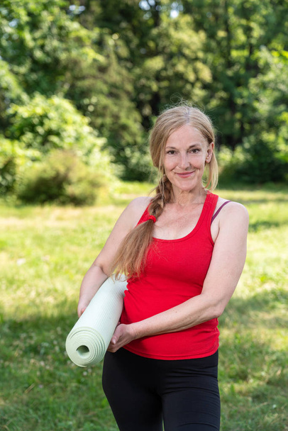 Kırmızı gömlekli bir parkta en iyi yaşlı bayan uygulama yoga - Fotoğraf, Görsel