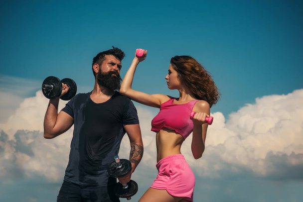 dumbbell lifting. sport and fitness. healthy lifestyle. dieting. freedom. bearded man and woman with fit belly. sporty couple training outdoor. perfect body muscle. summer activity. barbell equipment - Фото, зображення