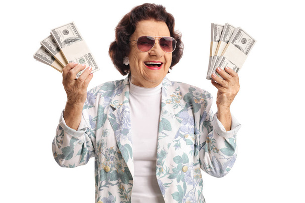 Cheerful elderly woman holding bunches of money and smiling - Fotoğraf, Görsel