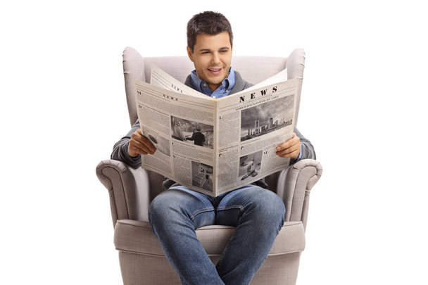 Guy sitting in an armchair and reading a newspaper - Fotó, kép
