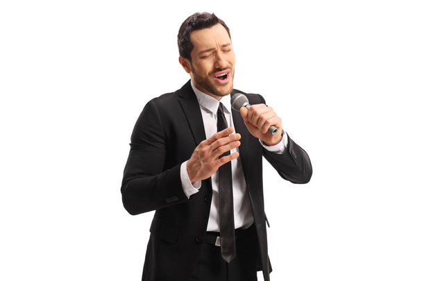 Чоловік співає на мікрофоні з емоційним виразом обличчя
  - Фото, зображення