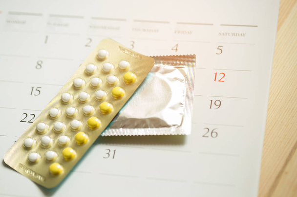 Протизаплідні таблетки і презервативи на дату календаря обчислюють дату Контроль народжуваності. настільний дерев'яний фон. охорона здоров'я та медицина, концепція контрацепції. порожній простір для тексту
. - Фото, зображення