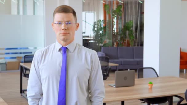 Young man in glasses is smiling in middle of office - Footage, Video