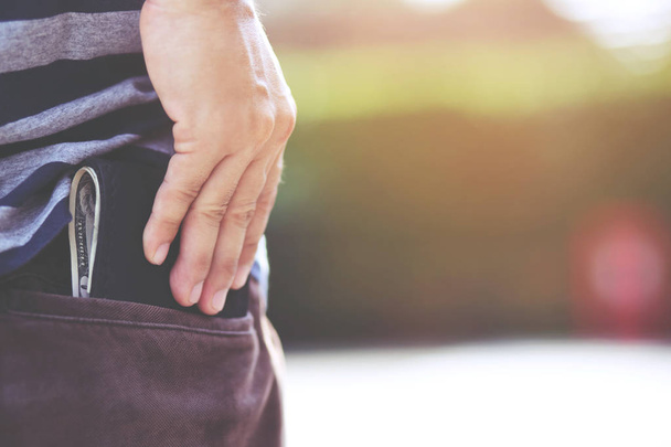Magabiztos fiatalember pózol biztonságban tartja a pénztárcáját a hátsó zsebében a hátán zseb nadrágot. pénzmegtakarítás. - Fotó, kép
