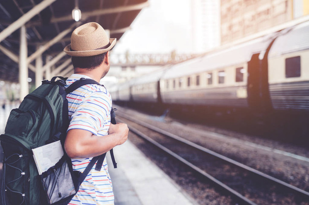 Pasażerowie czekają na peronie stacji. Młody człowiek podróżnik z plecakiem czeka na pociąg. podróż turystyczna Przygotuj się na wyjazd. - Zdjęcie, obraz