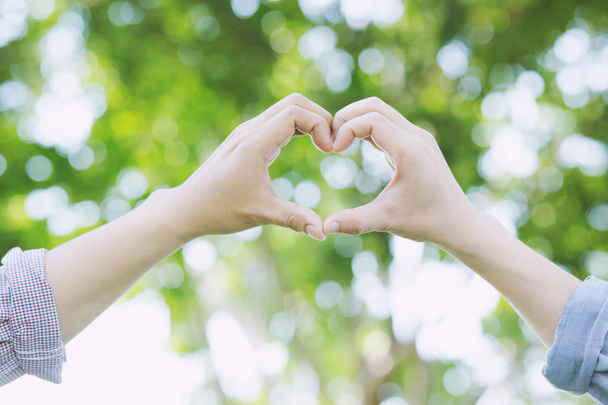 Молода пара коханців показують, як тримаються за руки роблять форму серця в громадських парках
. - Фото, зображення