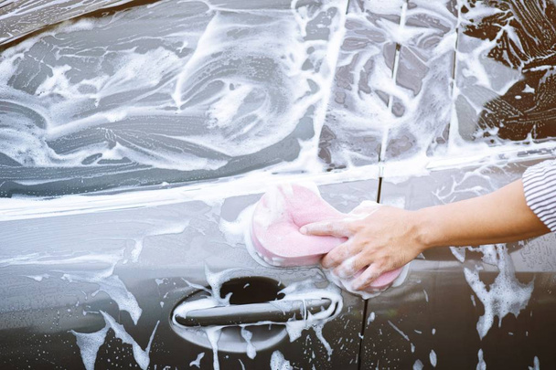 people man holding hand pink sponge for washing car. Concept car wash clean. - Foto, afbeelding