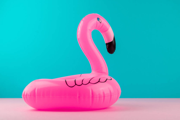 Inflatable mini flamingo on pastel blue and pink background. Pool float party, trendy summer concept. Flat lay, copy space. - Photo, image