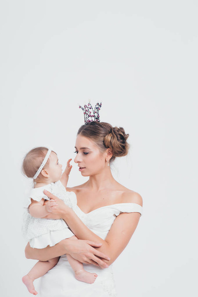 baby in the arms of the mother. on white background Woman holding a child. Fashion for girl. Queen with princess - Fotoğraf, Görsel