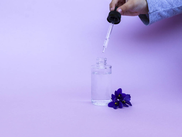 liquid in  transparent bottle with pipette for soaring electronic cigarettes with  scent and taste of flowers, on  pink background with space for text. - Foto, Imagen