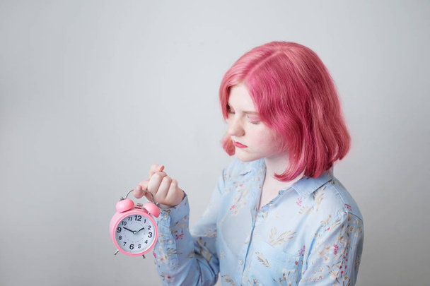 sad teenager girl with pink hair holding alarm clock - Foto, imagen