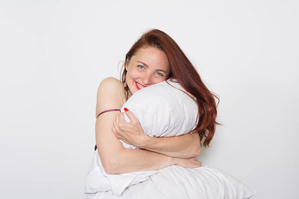 Smiling portrait of a woman leaning on a pillow over white background - Foto, Imagen
