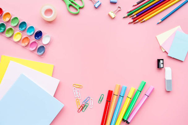School supplies stationery, colour pencils, paints, paper on pink background, back to school concept with free copy space for text, modern elementary education. Kids desk, flat lay, top view, mockup. - 写真・画像