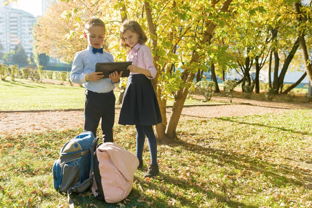 Two kids watching digital tablet, background autumn sunny park - Φωτογραφία, εικόνα