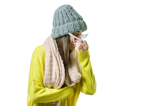 Woman caught a cold in warm hat and scarf with handkerchief, isolated on white background, flu season - 写真・画像