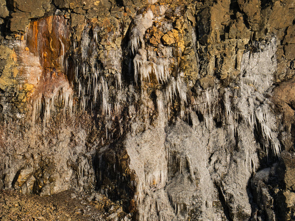 Çok küçük buz sarkıtları ile renkli bir kaya yüzü - Fotoğraf, Görsel