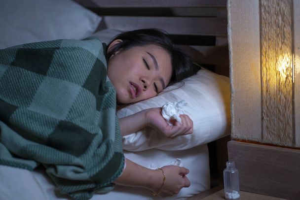 młody piękny zmęczony i chory Asian koreański kobieta leżącego na łóżku w domu chorych cierpiących na zimno grypy i temperatury pokryte koc uczucie złe i gorączkowe - Zdjęcie, obraz