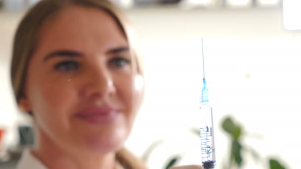 Retrato de uma esteticista feliz sorridente na clínica de beleza preparando a seringa para injeção olhando diretamente para a câmera. Feche a seringa focada. Conceito de profissionais. Conceito de beleza
 - Filmagem, Vídeo