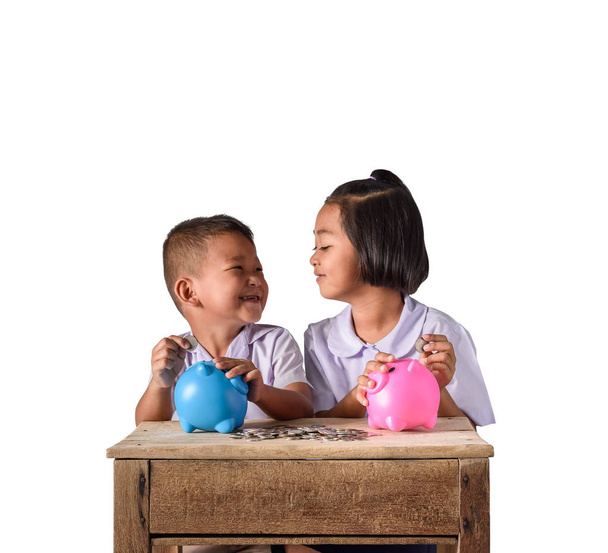 Милый азиатский деревенский мальчик и девочка положить монеты в копилку свиньи является
 - Фото, изображение