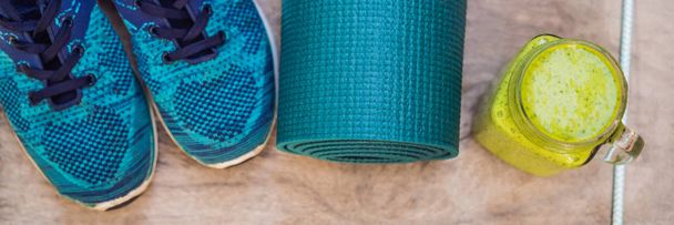 BANNER, LONG FORMAT Everything for sports turquoise, blue shades on a wooden background and spinach smoothies. Yoga mat, sport shoes sportswear and bottle of water. Concept healthy lifestyle, sport - Valokuva, kuva