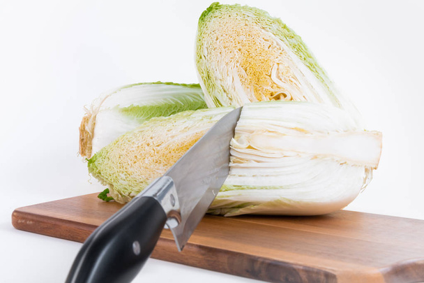 Two half of Chinese cabbage with knife on chopper board isolated on white background - Фото, изображение