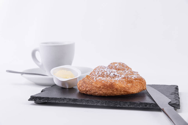 Sabroso panecillo de hojaldre con azúcar en polvo en la parte superior, mantequilla untada y café caliente
 - Foto, Imagen