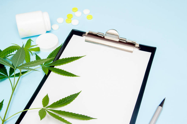 Top view of blank paper for writing doctor prescription. Marijuana leaf with medical pills on blue background. The concept of legalization of marijuana. - Fotó, kép