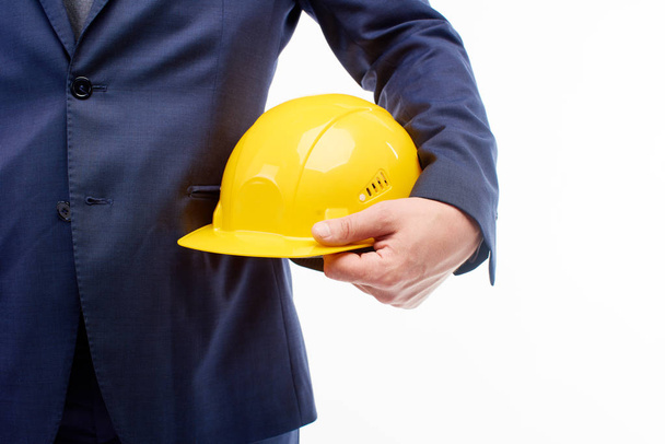 Close-up. Ploegbaas houdt een bouw helm in zijn handen op een witte achtergrond. - Foto, afbeelding