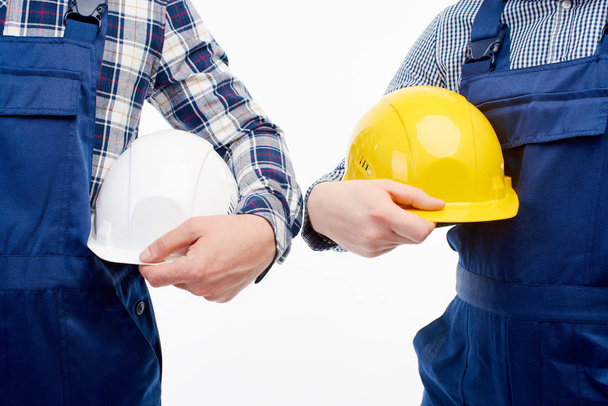 Closeup. Two engineers hold building helmets in their hands. - Foto, imagen