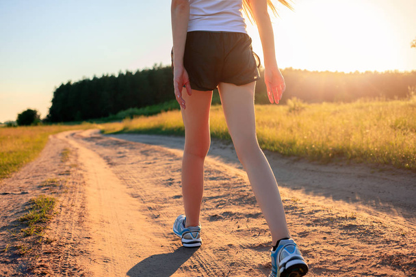 Jambes sport. Ferme là. pieds coureur athlète courir sur le chemin de terre à travers le champ au lever du soleil
. - Photo, image