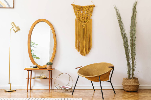 Stylish and minimalistic scandi interior of living room with design gold armchair, lamp, poster frames. dressing table with mirror, plants, palm leaves, yellow macrame and accessories. Cozy home decor - Foto, Bild