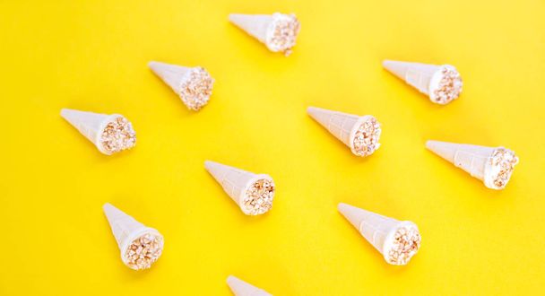 Trendy sunlight Summer pattern. Ice cream with nuts in waffle cups. Waffle cones laid out on a yellow background. - 写真・画像