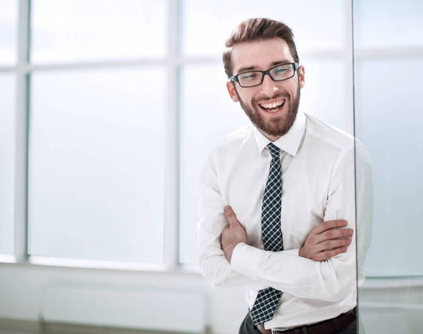 smiling businessman standing near the office window. - Fotografie, Obrázek